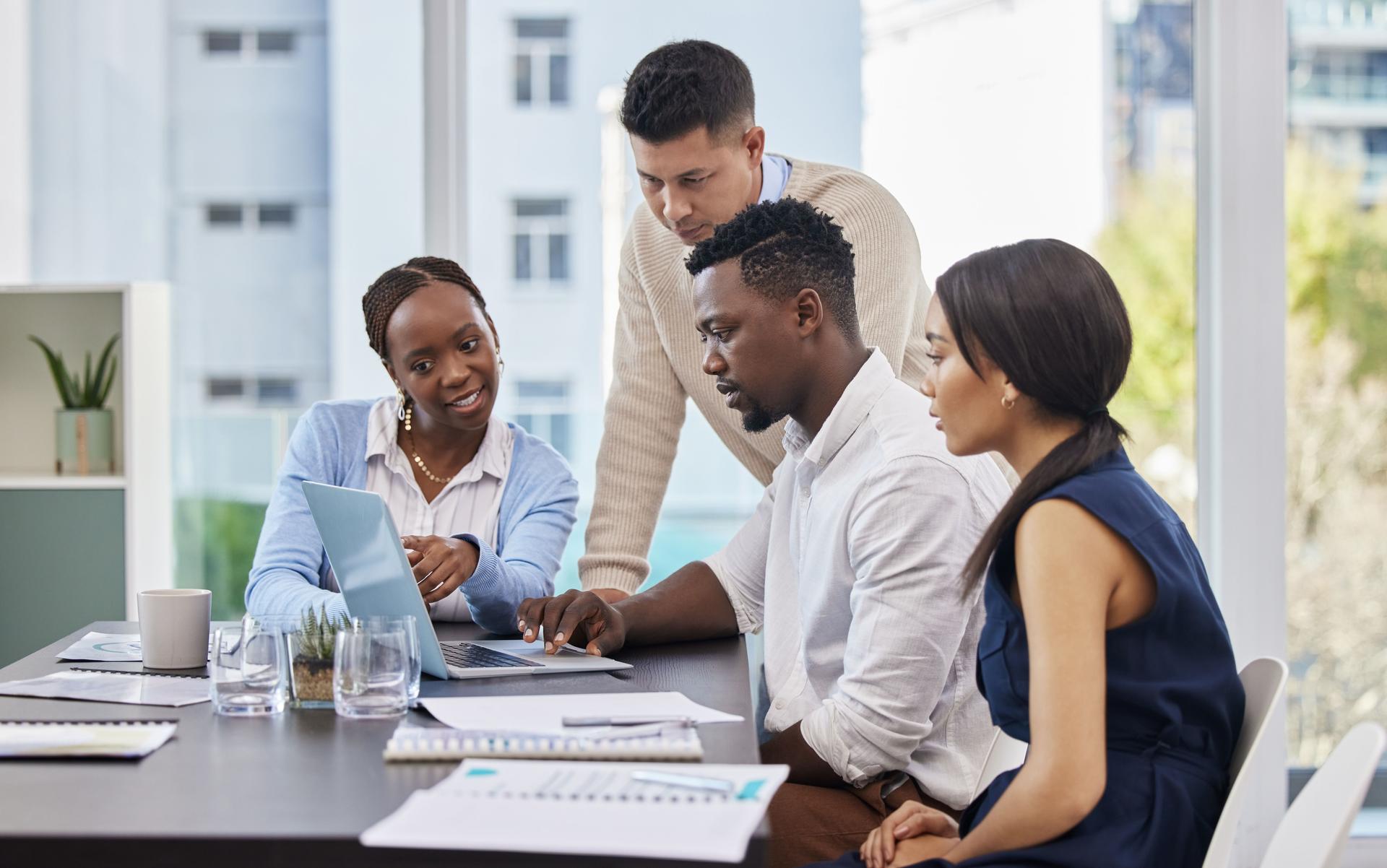 Shot of a group of business people brainstorming during a meeting while using a laptop