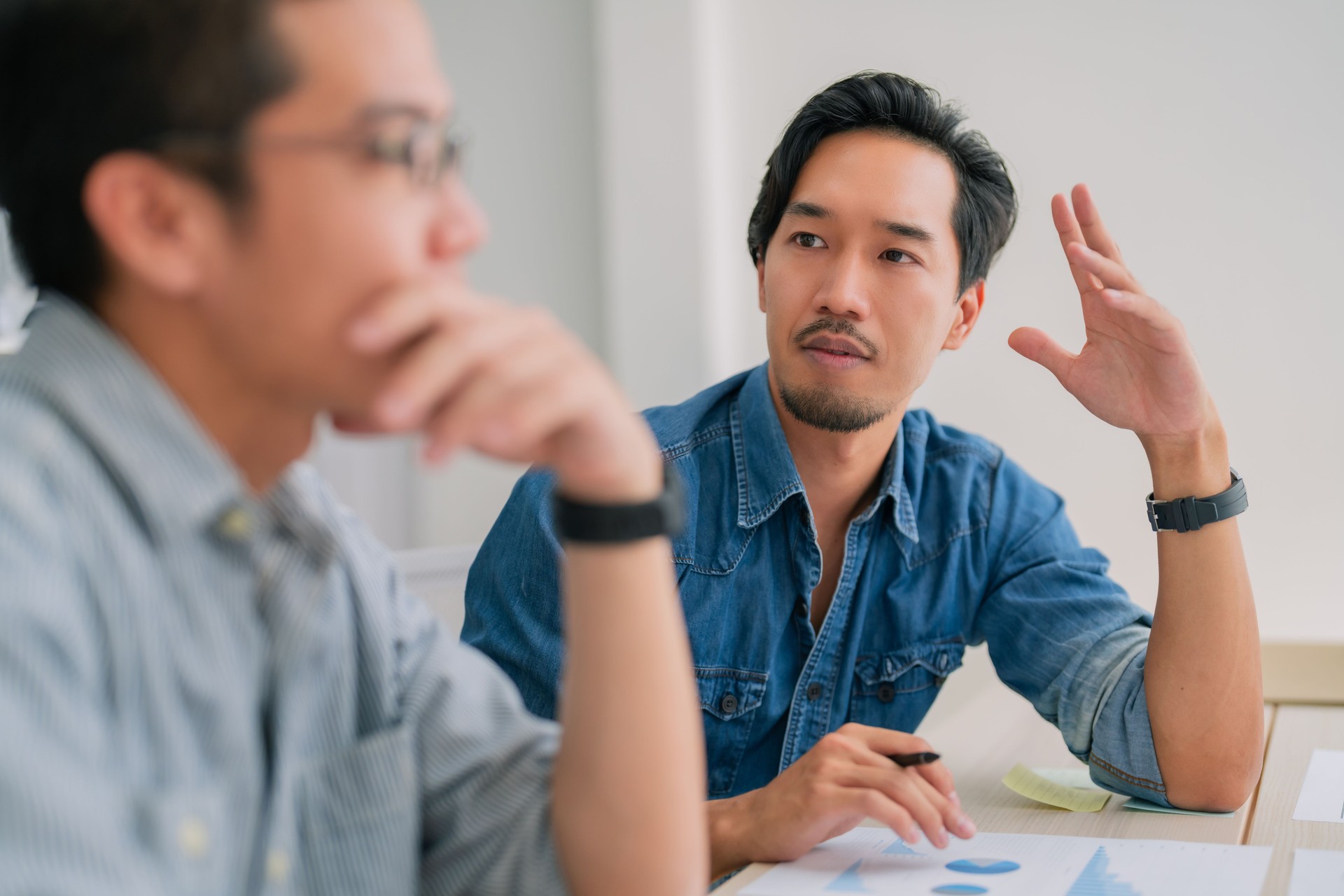 Focused discussion between two men in creative workspace, showcasing collaboration and brainstorming. atmosphere is engaging and productive, highlighting teamwork and communication